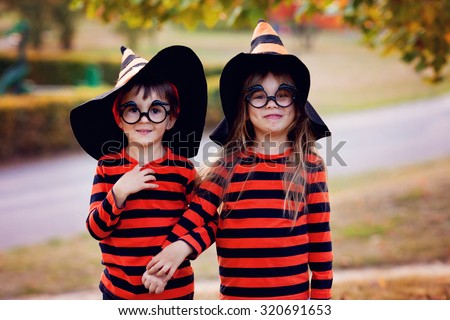 Boy and girl in the park in halloween costumes, having fun autumn time