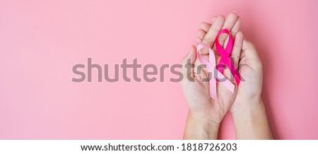 October Breast Cancer Awareness month, adult Woman  hand holding Pink Ribbon on pink background for supporting people living and illness. International Women, Mother and World cancer day concept