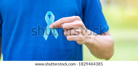 November Prostate Cancer Awareness month, Man in blue T shirt with hand holding Blue Ribbon for supporting people living and illness. Healthcare, International men, Father and World cancer day concept