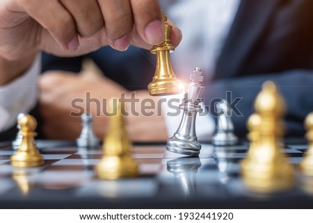 businessman hand moving gold Chess King figure and Checkmate opponent during chessboard competition. Strategy, Success, management, business planning, disruption and leadership concept Stockfoto © 