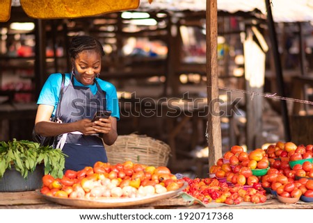 excited nigerian market woman feeling excited while using her phone