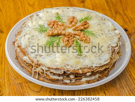 Liver cake with garlic, dill sauce and walnuts in the white plate on wooden table.