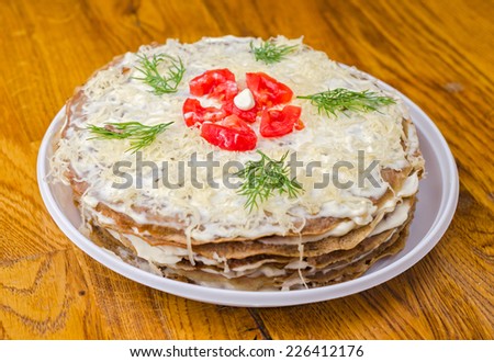 Liver cake with garlic, dill sauce and tomatoes in the white plate on wooden table.