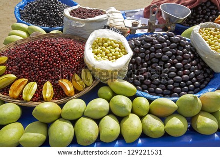 A fruit seller\'s cart on a Mumbai beach with a colorful selection of tropical fruits and nuts.