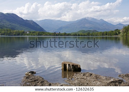 Lagho Piccolo or the Small Lake, Avigliana, Italy. A view across the tranquil lake to the snow capped mountains beyond.