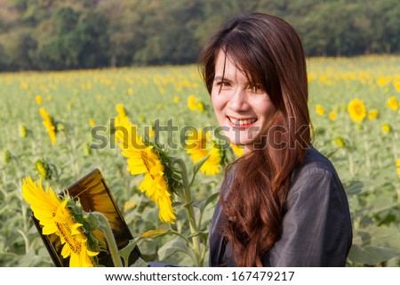 Young pretty business woman with notebook on sunflower field