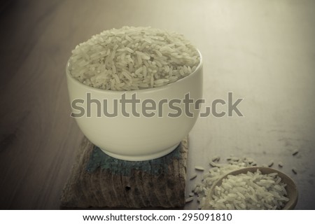 Uncooked rice in a bowl on wooden table.