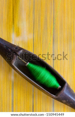 green threads in shuttle loom on yellow threads