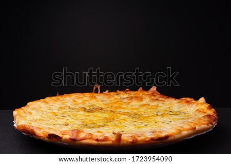 Simple four cheese delivered pizza with crunchy crest and golden yellow orange tint studio low key still life against a dark background