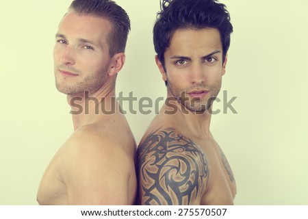 two handsome men posing back to back