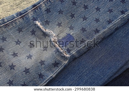 Close up of destroyed torn denim blue jeans with patch and star stamp