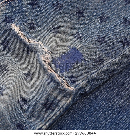 Close up of destroyed torn denim blue jeans with patch and star stamp, crop