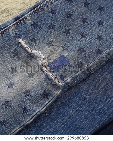 Close up destroyed torn denim blue jeans with patch and star stamp, crop; top view