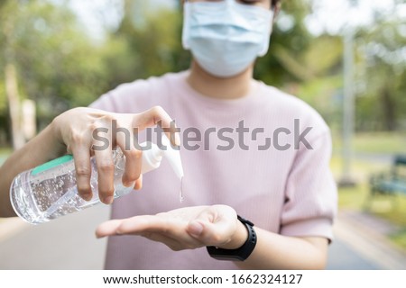 Asian people using alcohol antiseptic gel and wearing prevention mask,prevent against infection of Covid-19 outbreak,woman washing hands with hand sanitizer to avoid contaminating with Corona virus  