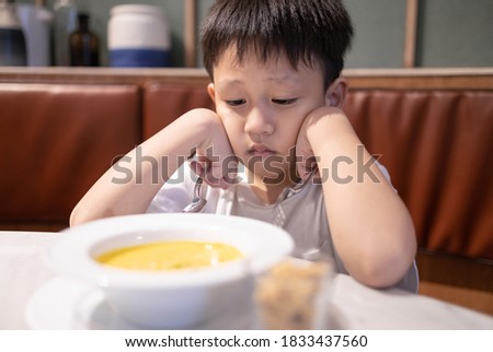 Depressed asian kid boy with anorexia,don't have appetite,child kindergarten bored with food or boredom,refusing to eat vegetable soup,unpalatable,tired of food,nutrition and eating disorder concept Stock foto © 