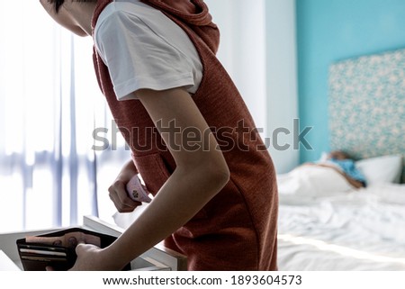 A thieving teen girl with kleptomania disease,taking money from a leather wallet in drawer of desk,stealing money,asian woman tries to quietly steal cash her father's money while her parent sleep Сток-фото © 
