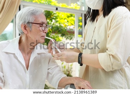Asian caregiver take care of senior woman give drinking water from a glass,feeding water using a straw to prevent choking at nursing home,thirsty elderly patient sucking water through straw for safety Stockfoto © 