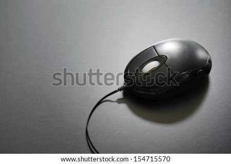 Black computer mouse and cable on black background with copy space
