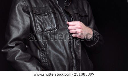 Leather jacket with hand pulling zip on black background.