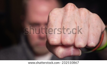 Aggressive or positive man punching the air with fist coming into camera on black background.