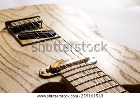 Electric guitar body section, with pick-ups and guitar strings in morning sunlight.