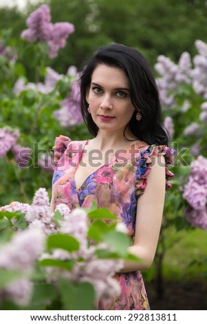 Beautiful cute girl in lilac flowering trees in the summer warm day