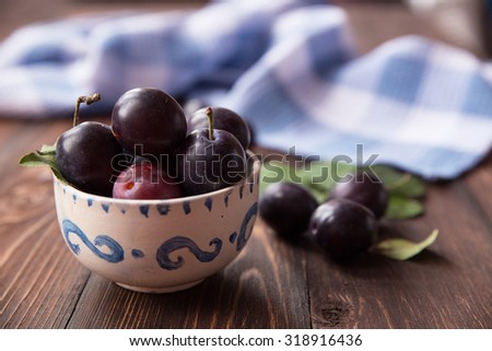 Plums with leaves and napkin on wooden table. Selective soft focus