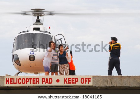 CAIRNS, AUSTRALIA - AUGUST 2008: Asian tourists being photographed after a helicopter flight on green island, north queensland, australia