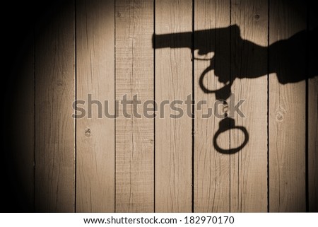 Male Hand shadow with Gun and Handcuffs on Natural Wood Background. You can see more crime scene in my set.