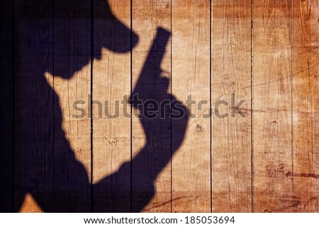 Man with a gun in shadow on a wooden background. You can see more silhouettes and shadows on my page.