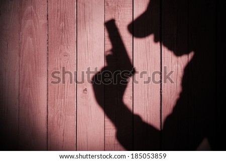Gangster or investigator or spy silhouette on natural wooden wall. You can see more silhouettes and shadows on my page.