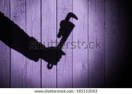 Human hand shadow with adjustable wrench  on the wood background, with space for text or image. You can see more silhouettes and shadows on my page.