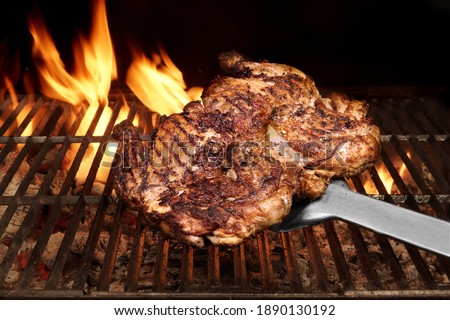 Juicy Chicken Meat Roasted on BBQ Grill. Whole Chicken Grilled On Hot Barbecue Charcoal Flaming Grill.  Backyard Grill Party Dish From Poultry Isolated On Black Background, Closeup View.