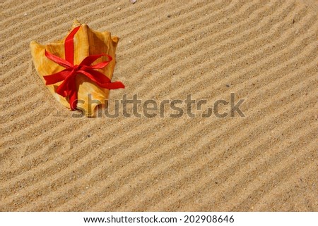 Sea Shell with red ribbon and gold sand. Summer Marine Background with space for text or image