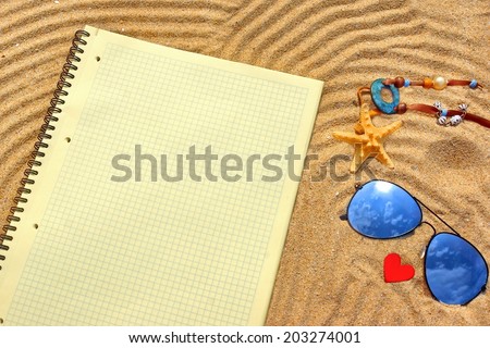 Sunglasses, Yellow checkered notepad and  different objects on the beach sand. Marine Summer Background.