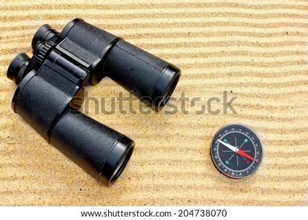 Sea Binoculars and Compass isolated on the sand background
