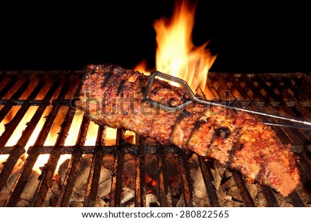BBQ Roast Marinated Baby Back Pork Ribs Close-up On Hot Flaming Grill Background