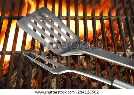BBQ Tools Spatula Flipper Fork On The Hot Flaming Charcoal Grill Background