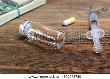Medical Syringes, Vial  And Wad Of Dollar Bills On The Rough Wooden Background. Medical Mistake Or Drug Abuse Concept