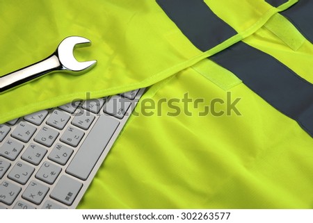 Keyboard In The Yellow  Safety Reflective Vest And Wrench. Technical Or Road Assistance Concept With Copy Space