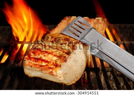 Big Chop Of Pork Ribs On The Hot BBQ Grill With Flames On The Black Background. Cookout Scene
