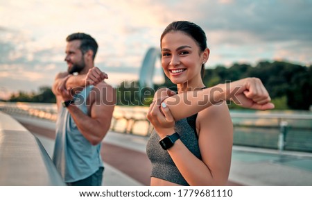 Couple stretching outdoors before morning run. Handsome bearded man and attractive sporty woman running on the street.