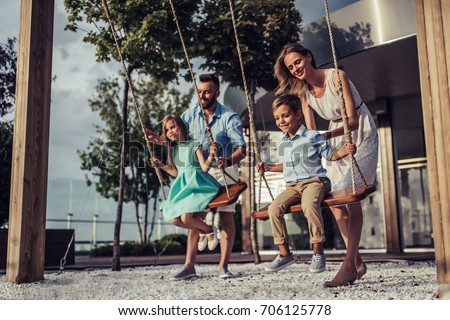Image, Stock Photo Father and mother swinging their baby sitting on the green grass in the park. Infant is laughing happy.