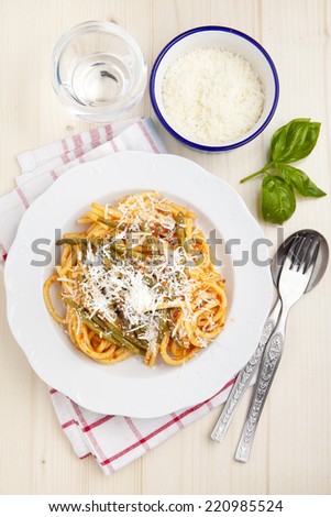 pasta with tomato sauce and green beans. Parmesan cheese. fresh basil. on wooden table
