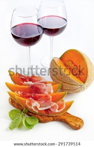 Slices of melon cantaloupe with prosciutto ham & wineglasses with wine. healthy snack