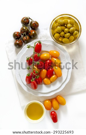 various types of cherry tomatoes: red, yellow and black Sicilian. on a wooden cutting board. on white.