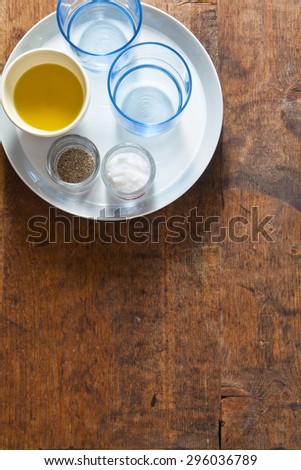 Serving dinner table. two empty blue glasses, olive oil, salt and pepper on the empty plates. on a wooden table. background for restaurants