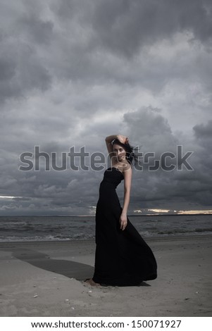 Model posing on ocean coast during sunset