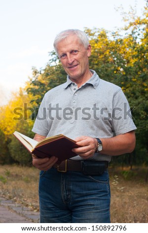 skinny  old man holding book and smiling in the park outdoor