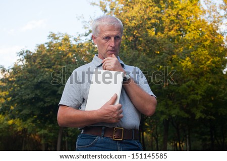 pensive old man with book in the hands. Blue jeans. Grey t-shirt. Watch